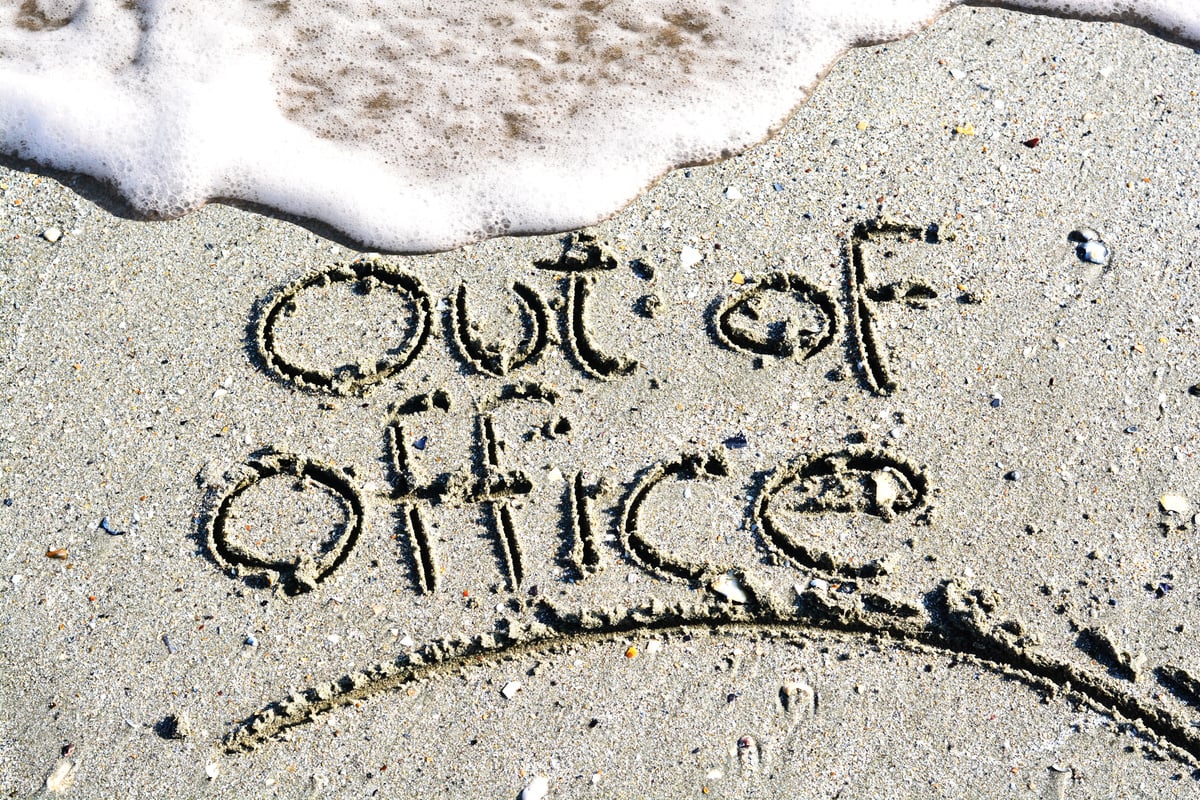 Out of office text written on the beach